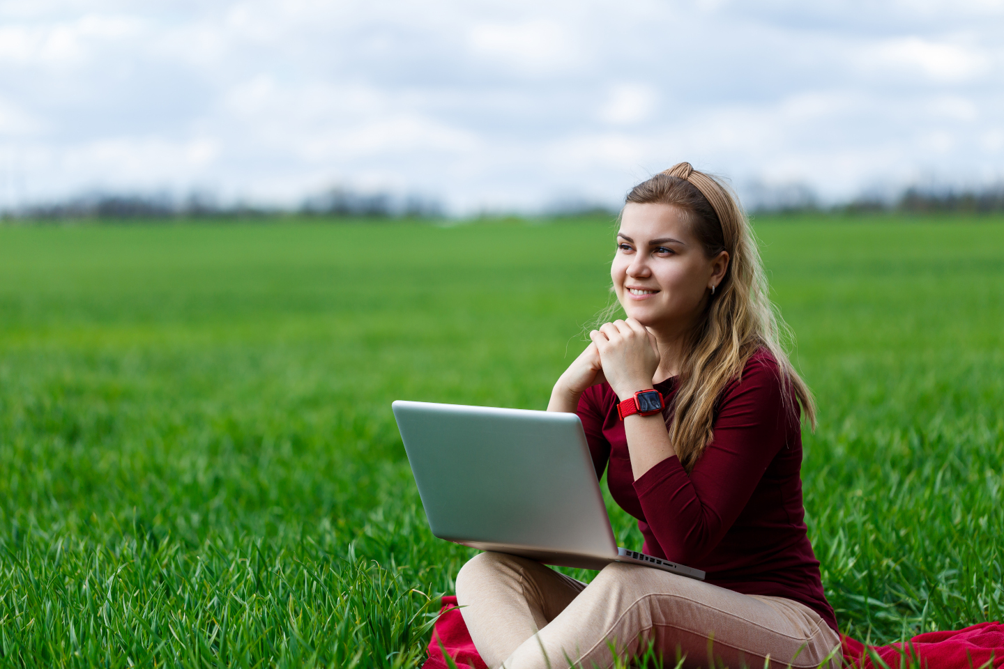 Person sitting on grass with laptop.